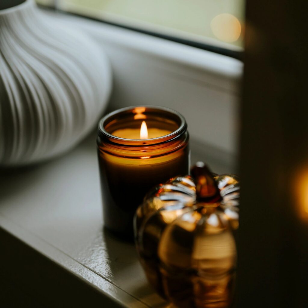 Still life on window sill with glass pumpkin and scented candle for autumn